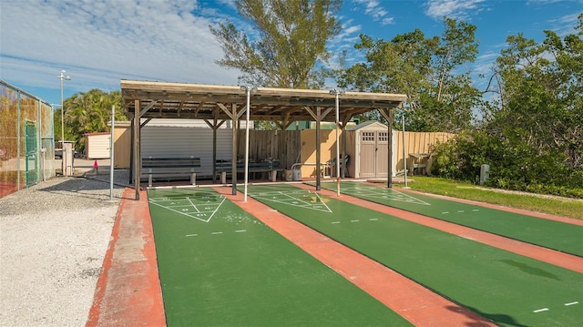 view of community featuring fence and shuffleboard