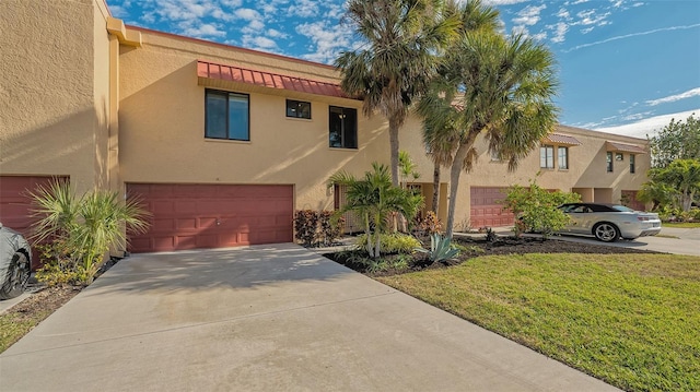 view of front of home featuring a garage, driveway, a front yard, and stucco siding