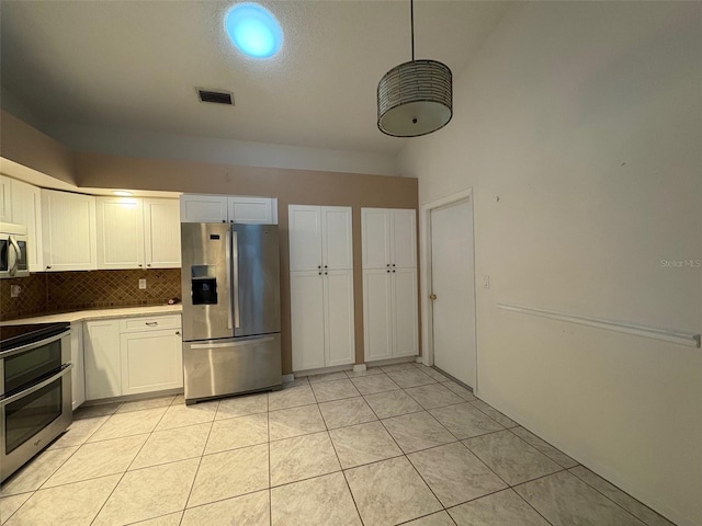 kitchen with decorative light fixtures, light tile patterned floors, appliances with stainless steel finishes, decorative backsplash, and white cabinets