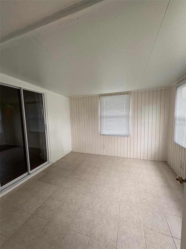 tiled spare room featuring wood walls