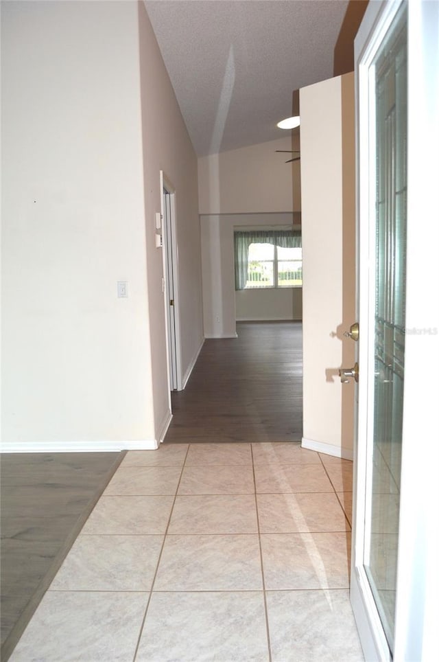 hall featuring lofted ceiling, light tile patterned floors, baseboards, and french doors