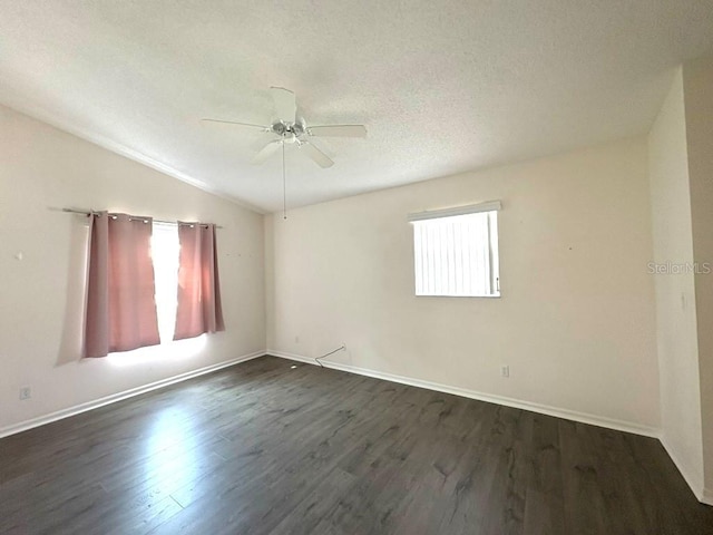 spare room featuring baseboards, dark wood-style floors, ceiling fan, vaulted ceiling, and a textured ceiling