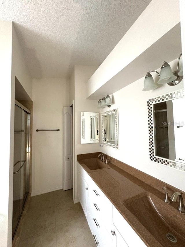 full bathroom with a stall shower, tile patterned flooring, and a sink