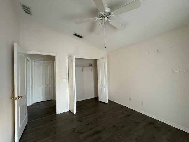 unfurnished bedroom with lofted ceiling, dark wood-style flooring, and visible vents