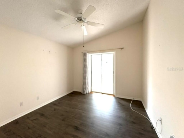 unfurnished room featuring baseboards, dark wood finished floors, a ceiling fan, vaulted ceiling, and a textured ceiling