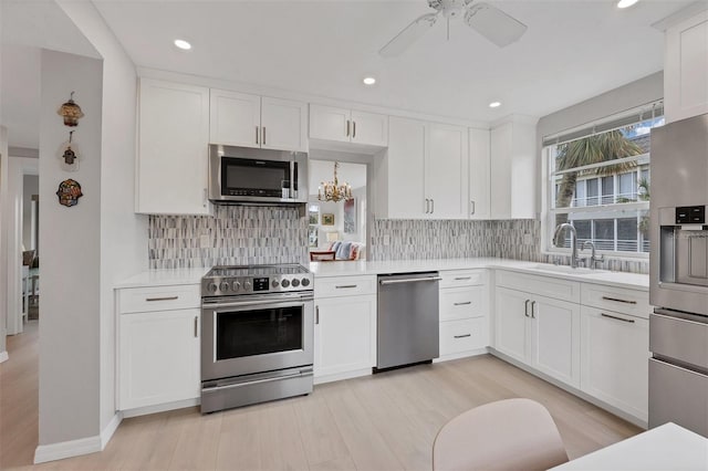 kitchen featuring white cabinets, stainless steel appliances, a sink, and light countertops