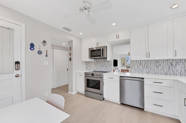 kitchen with ceiling fan, appliances with stainless steel finishes, light countertops, white cabinetry, and backsplash