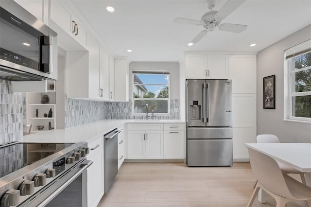 kitchen with light wood-style flooring, white cabinetry, light countertops, appliances with stainless steel finishes, and backsplash