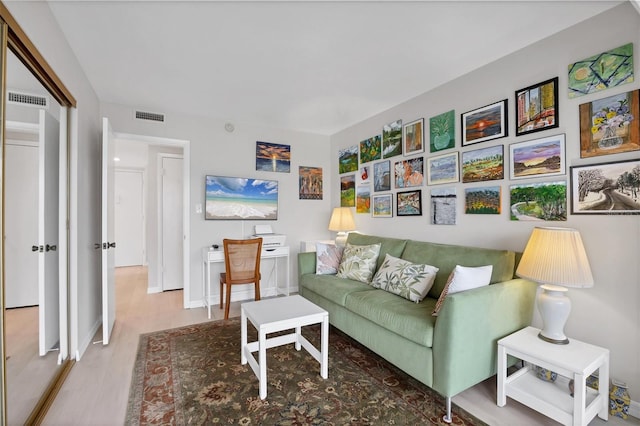 living area featuring visible vents, baseboards, and wood finished floors