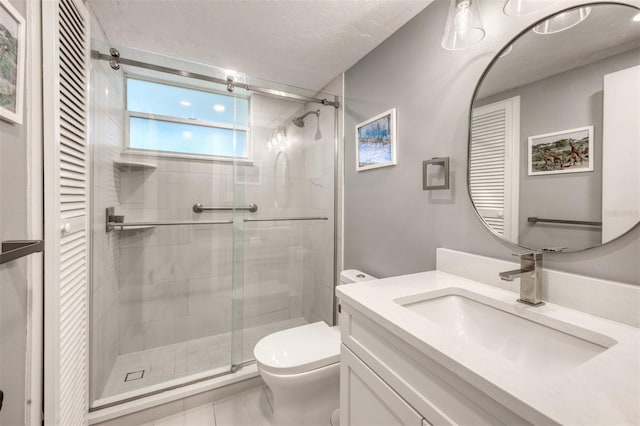 full bathroom featuring toilet, a shower stall, a textured ceiling, and vanity