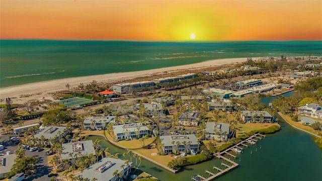 aerial view at dusk with a water view and a beach view