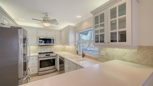 kitchen featuring light countertops, backsplash, appliances with stainless steel finishes, white cabinets, and a sink