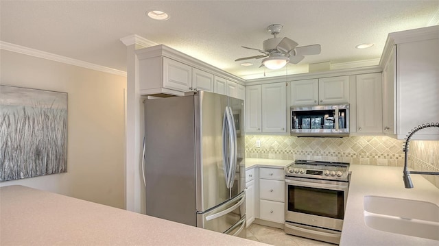 kitchen with light countertops, decorative backsplash, appliances with stainless steel finishes, ornamental molding, and a sink