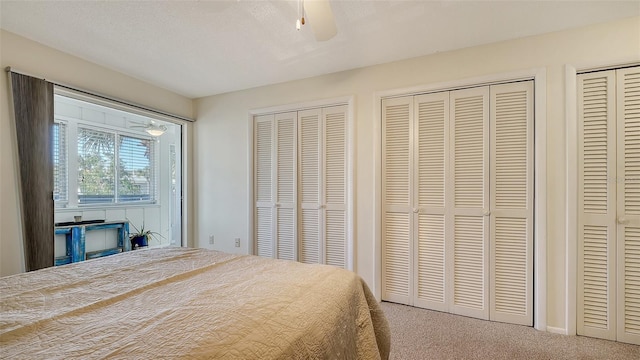 carpeted bedroom featuring multiple closets, ceiling fan, and a textured ceiling