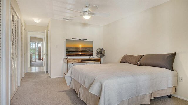 bedroom with light carpet, ceiling fan, visible vents, and baseboards