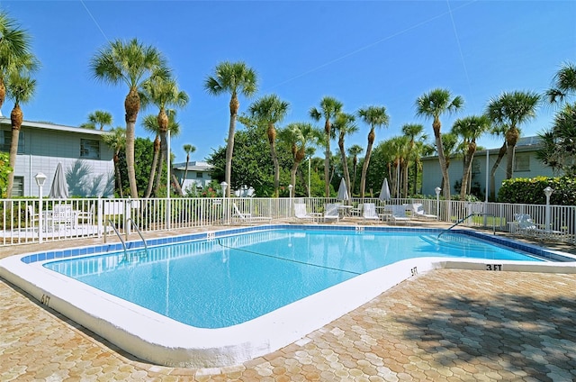 community pool with a patio area and fence