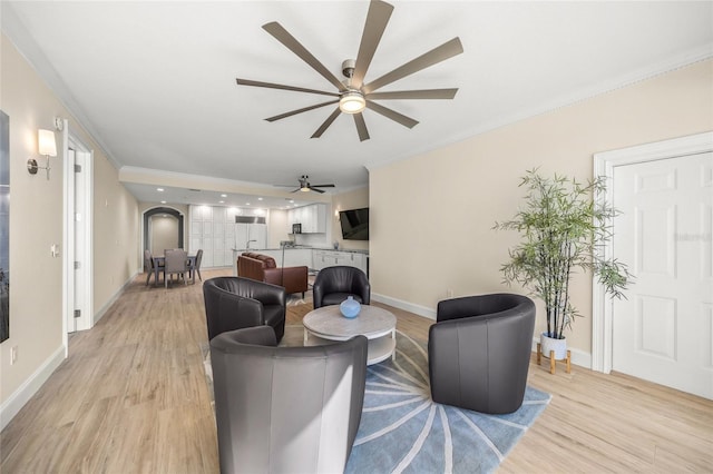 living room with crown molding, ceiling fan, and light wood-type flooring