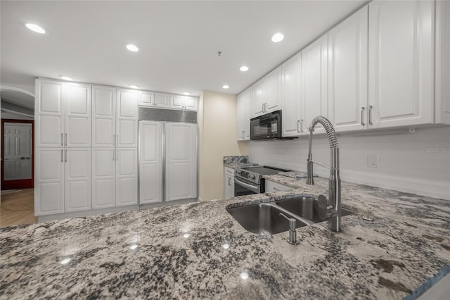 kitchen featuring paneled refrigerator, stainless steel electric stove, dark stone counters, and white cabinets