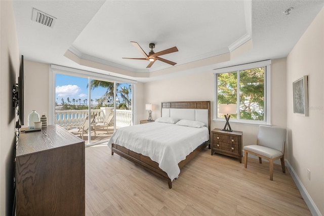 bedroom with access to outside, ceiling fan, a raised ceiling, crown molding, and light hardwood / wood-style flooring