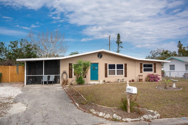 ranch-style house featuring a front yard, a carport, and a sunroom