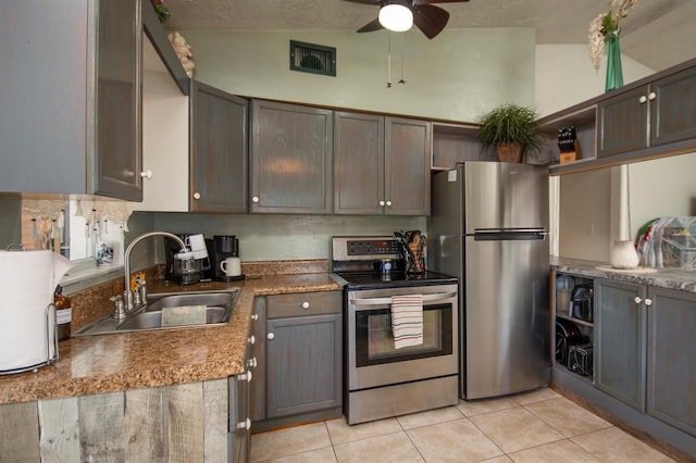 kitchen with ceiling fan, lofted ceiling, sink, stainless steel appliances, and light tile patterned flooring