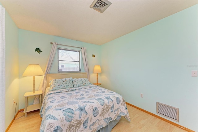 bedroom featuring visible vents, baseboards, and wood finished floors