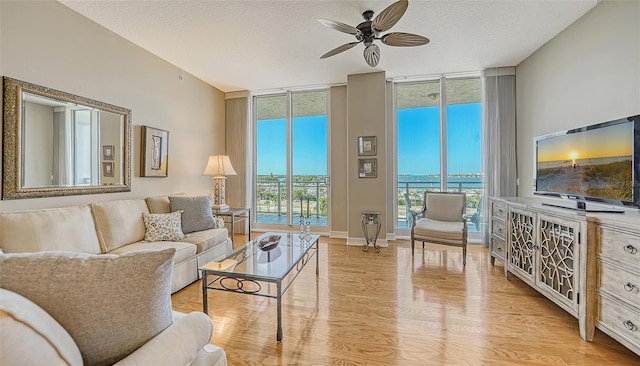 living room featuring light hardwood / wood-style flooring, floor to ceiling windows, and a textured ceiling