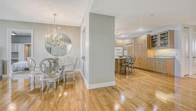 dining room with light wood-type flooring, a chandelier, and a textured ceiling