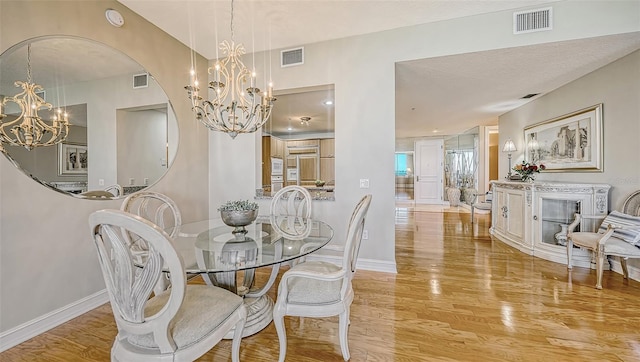 dining room featuring an inviting chandelier, a fireplace, a textured ceiling, and light wood-type flooring