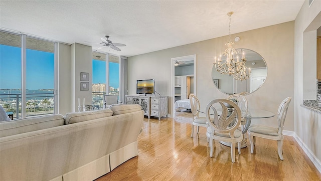 living room with hardwood / wood-style floors, ceiling fan with notable chandelier, a wealth of natural light, and a wall of windows