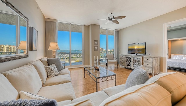 living room with a textured ceiling, light hardwood / wood-style floors, floor to ceiling windows, and ceiling fan