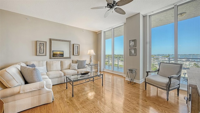 living room with floor to ceiling windows, ceiling fan, a textured ceiling, and light hardwood / wood-style floors