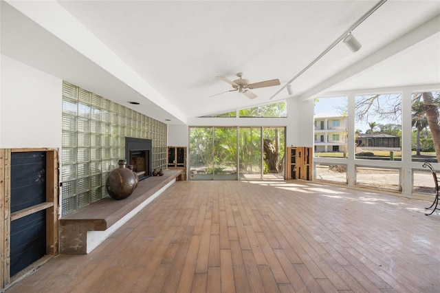 unfurnished sunroom featuring ceiling fan, a large fireplace, track lighting, and vaulted ceiling