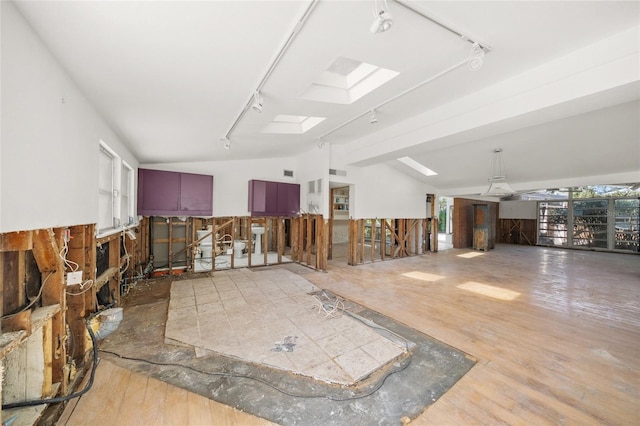 miscellaneous room with track lighting, vaulted ceiling with skylight, and hardwood / wood-style floors