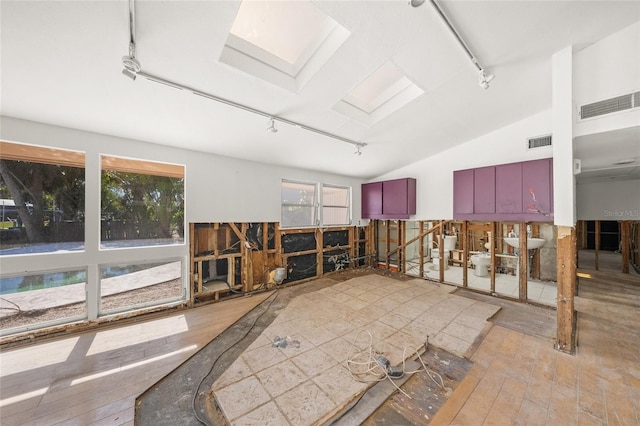 miscellaneous room featuring hardwood / wood-style flooring, track lighting, and lofted ceiling with skylight