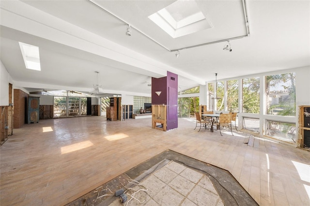 miscellaneous room featuring a wall of windows, ceiling fan, hardwood / wood-style floors, a skylight, and track lighting