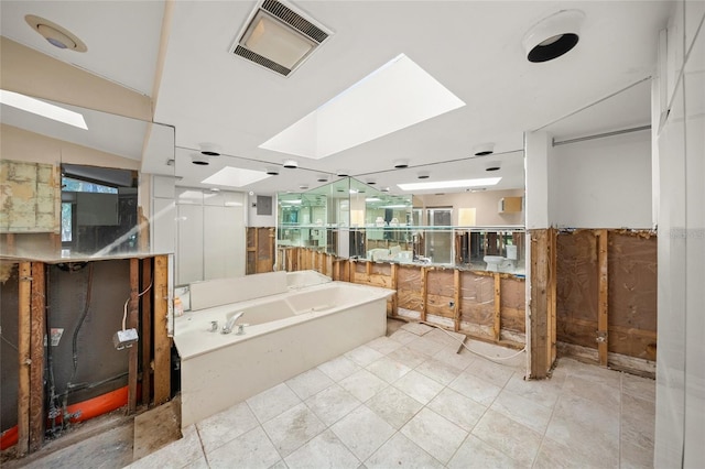 bathroom with vanity, a bath, and vaulted ceiling with skylight