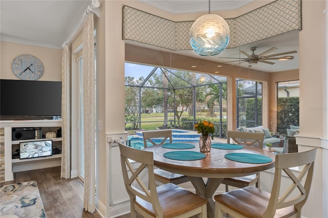 dining area with dark wood-type flooring, ceiling fan, and ornamental molding