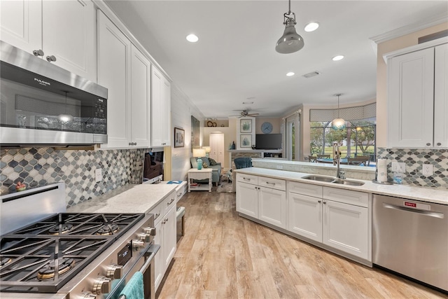 kitchen with appliances with stainless steel finishes, sink, hanging light fixtures, and white cabinets