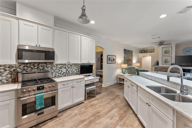 kitchen with sink, white cabinetry, stainless steel appliances, light stone countertops, and decorative light fixtures