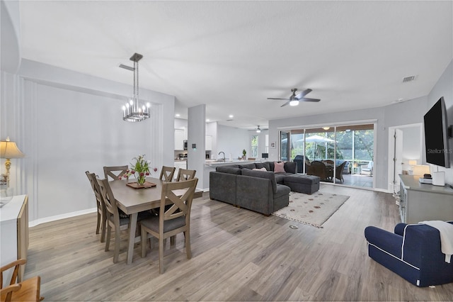 dining room featuring sink, ceiling fan with notable chandelier, and light hardwood / wood-style floors