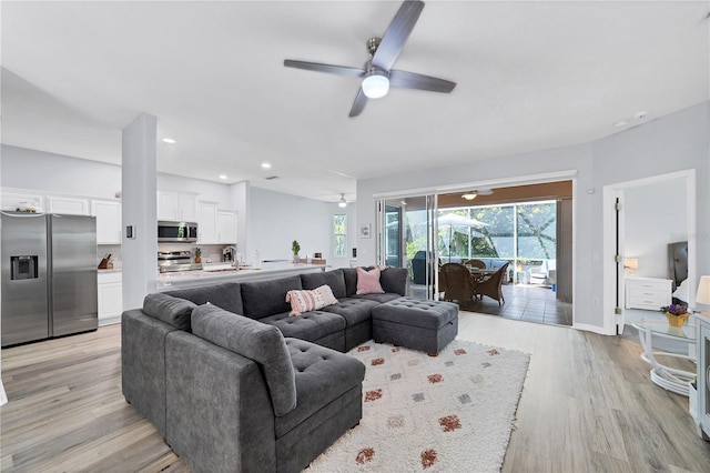 living room with ceiling fan, sink, and light wood-type flooring