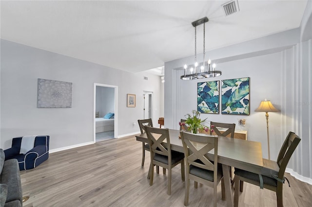 dining area with hardwood / wood-style flooring and a notable chandelier