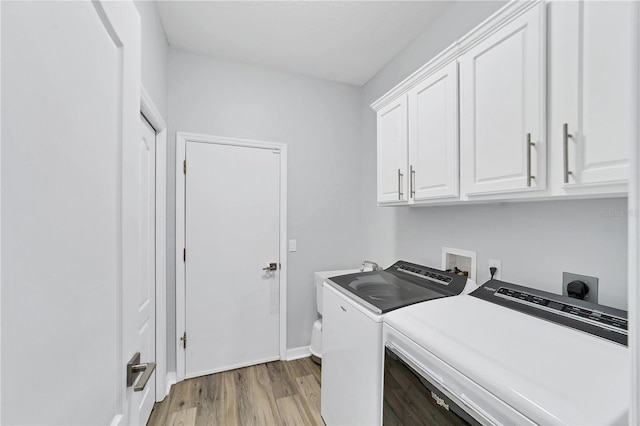 clothes washing area with cabinets, independent washer and dryer, and light hardwood / wood-style floors