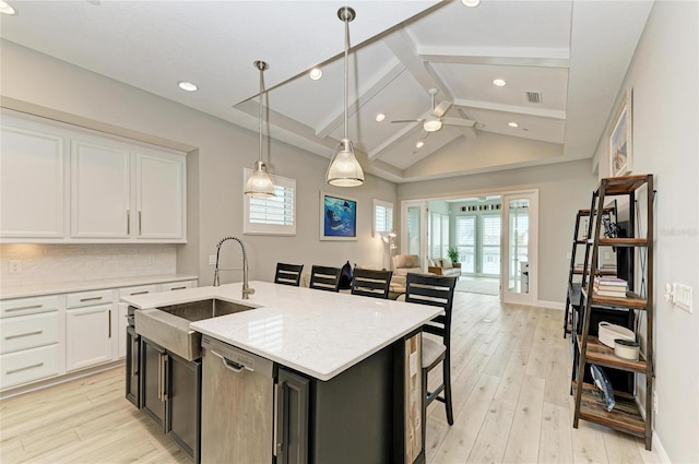 kitchen with pendant lighting, sink, dishwasher, white cabinetry, and an island with sink