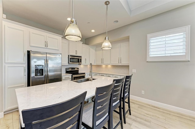 kitchen featuring appliances with stainless steel finishes, decorative light fixtures, white cabinetry, sink, and backsplash