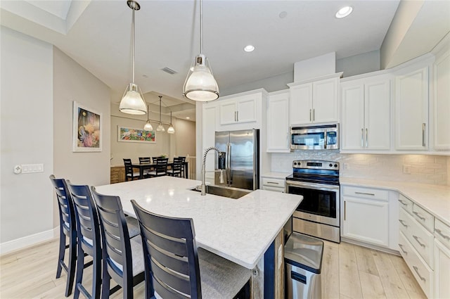 kitchen featuring white cabinetry, pendant lighting, a center island with sink, and appliances with stainless steel finishes