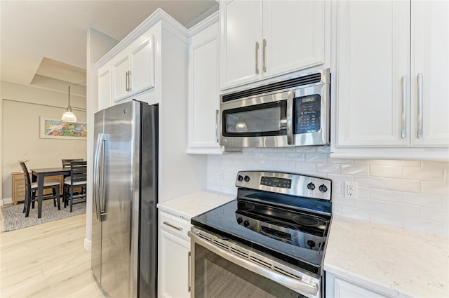 kitchen with decorative backsplash, white cabinets, and appliances with stainless steel finishes