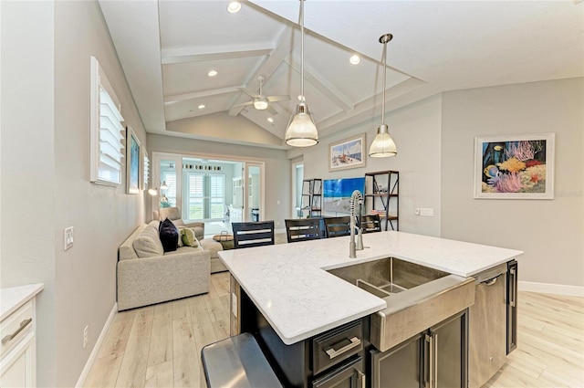 kitchen featuring a kitchen island with sink, hanging light fixtures, sink, and light wood-type flooring