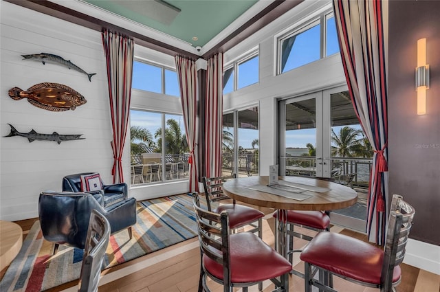 dining area with a towering ceiling, a wealth of natural light, french doors, and light wood-type flooring